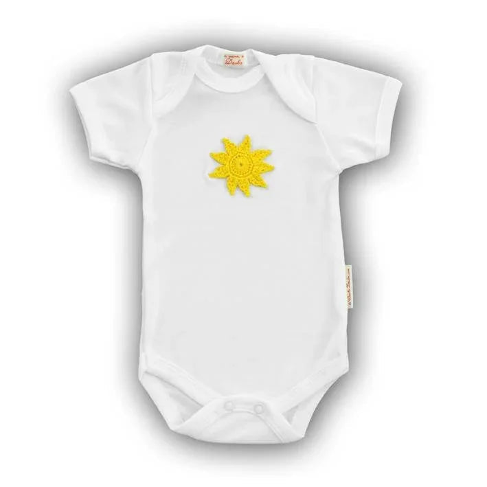 White Norvella baby onesie featuring a yellow hand-crocheted sun applique on the chest.