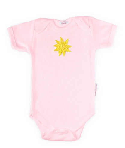 Pink Norvella baby onesie featuring a hand-crocheted yellow sun design.
