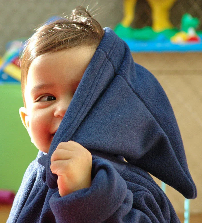 A toddler wearing a navy blue Norvella hood jumper, partially hiding their face.